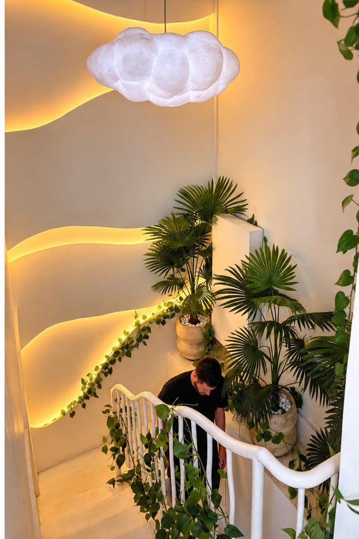 Café staircase with a cloud lamp, warm wave lighting and palms